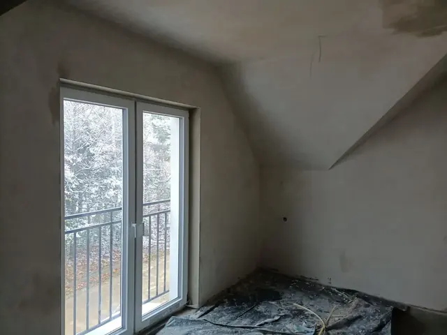 Tynki na ścianach i skosie sufitu w pokoju na poddaszu z oknem balkonowym — Krosno