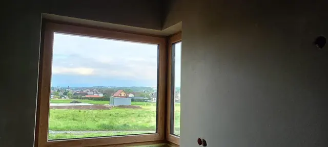 Tynki ścian w pokoju z oknem narożnym w okleinie drewnopodobnej — Stara Wieś